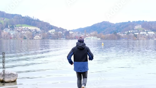 lake lucerne in switzerland, middle-aged man, 60-69 years old, in a winter blue jacket, runs on the beach, has fun in sports, the concept of a healthy lifestyle, physical activity photo