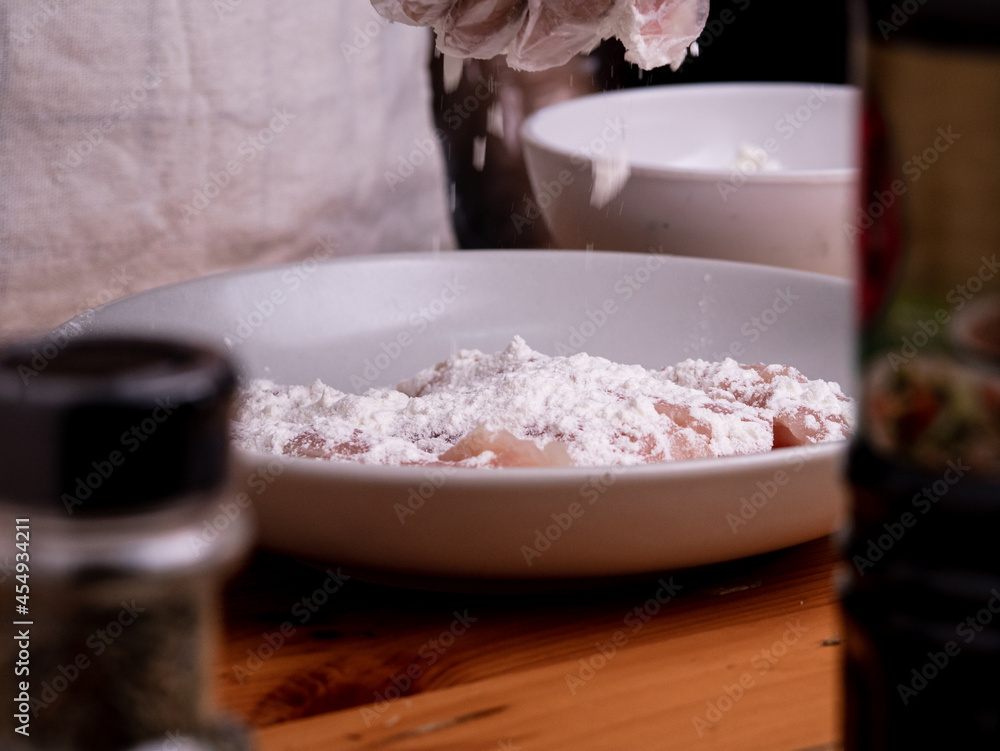 Hand of a woman wearing gloves is marinating chicken pieces in a bowl with soy sauce and flour to make delicious fried chicken at home. Cooking concept. Hand of a woman wearing gloves is marinating chicken pieces in a bowl with soy sauce and flour to make delicious fried chicken at home. Cooking concept.