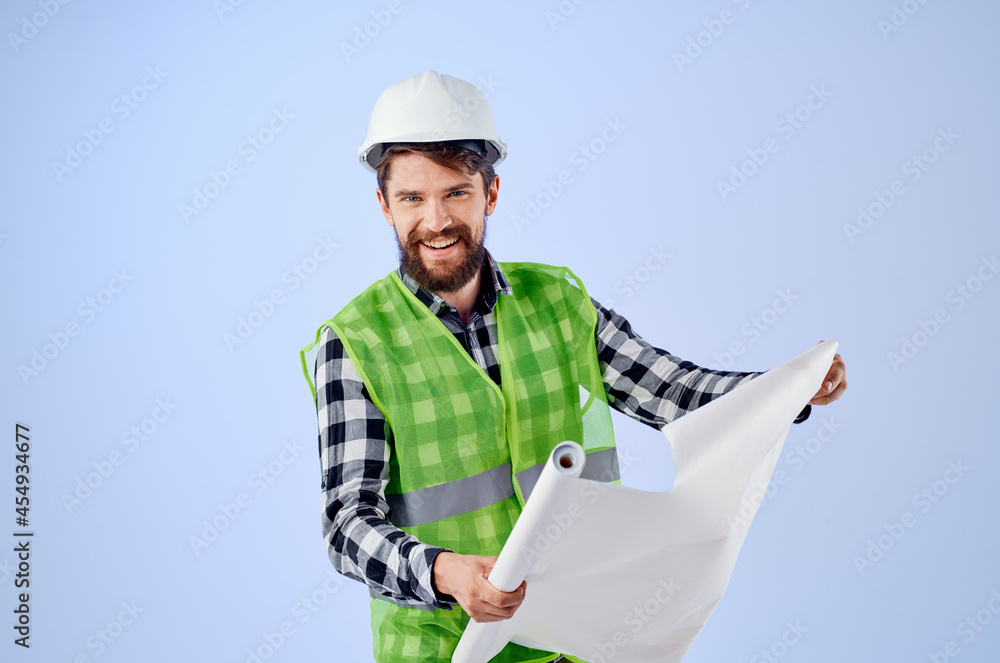 male builder in a white helmet blueprints Professional blue background male builder in a white helmet blueprints Professional blue background