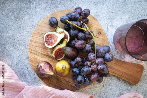 Wooden kitchen board with fresh figs and grapes