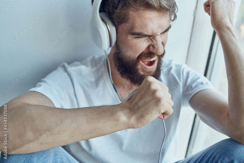 man in white t-shirt sitting in the room with headphones rest man in white t-shirt sitting in the room with headphones rest