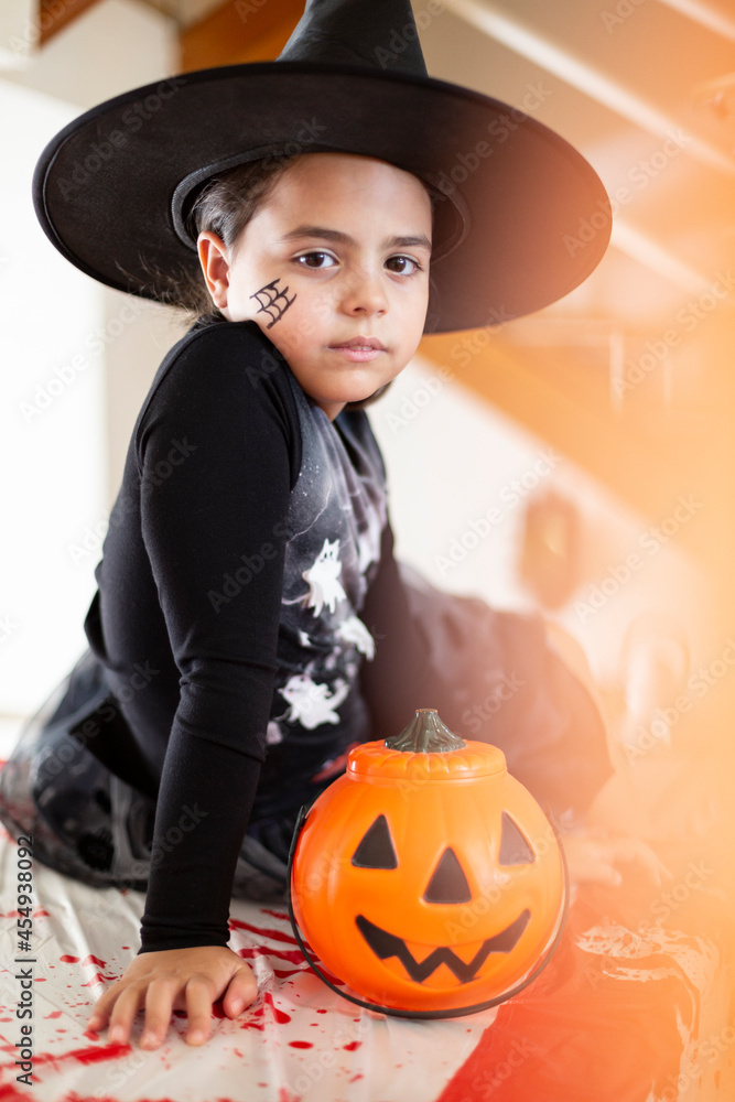 Portrait of caucasian little girl in witch costume next to a pumpkin. Halloween party. Portrait of caucasian little girl in witch costume next to a pumpkin. Halloween party.