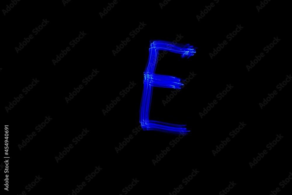 Drawn letter E with blue lights against black background. Light painting alphabet. Drawn letter E with blue lights against black background. Light painting alphabet.