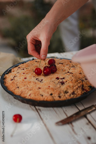 hand putting berries on a cake 