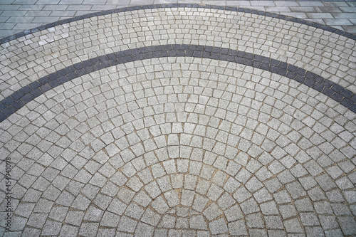 Paving stone laid in a semicircle. Well visible pattern of stones. Top view of the square from the old pavers