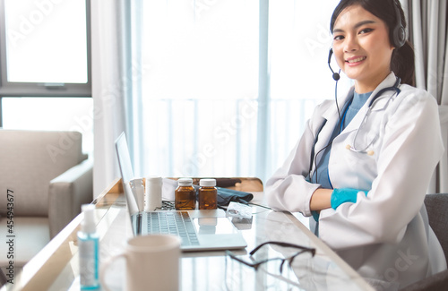 Portrait of young asian woman doctor with white coat standing in hospital.Telemedicine  Medical online  e health concept. Doctor using laptop for work.Remote medical help for distance patient advice.