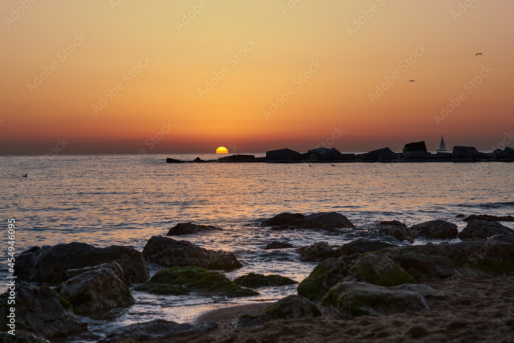 sailing boat on the horizon near to the sun at sunset barcelona