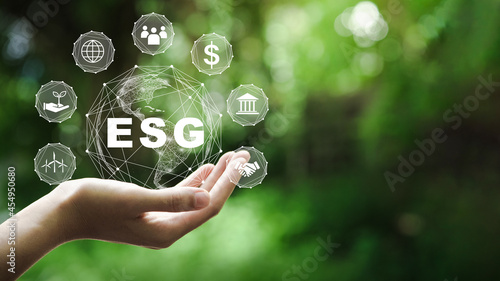 ESG icon concept in the hand for environmental, social, and governance in sustainable and ethical business on the Network connection on a green background. photo