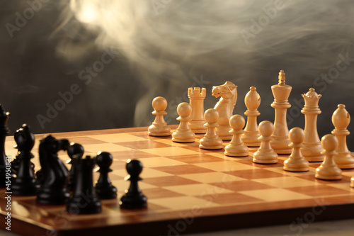 Chessboard with game pieces on grey background