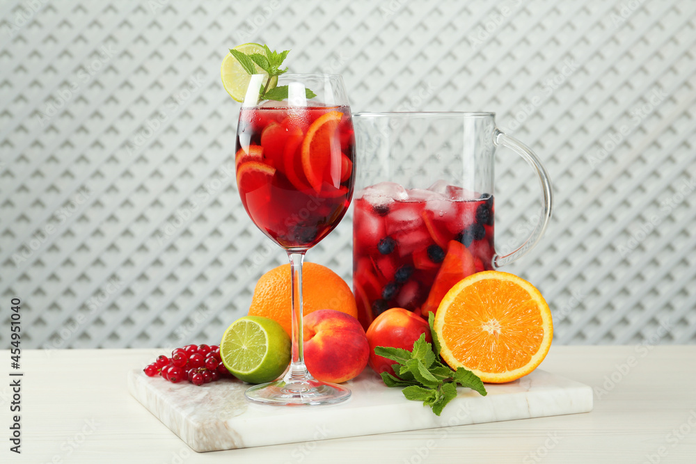 Glass and jug of Red Sangria with fruits on white wooden table Glass and jug of Red Sangria with fruits on white wooden table