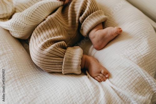 Fotografía Closeup of barefoot baby feet in knitted brown pants.