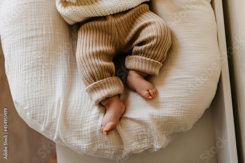 Closeup of baby feet in knitted brown pants. photo