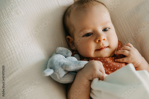 Closeup portrait of a three months old baby hugging a plush toy. photo