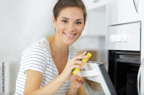 woman cleaning oven in kitchen