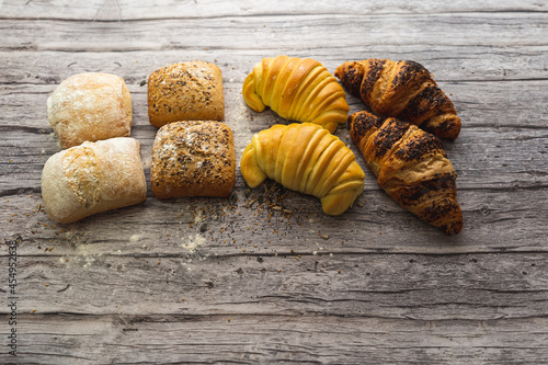 Bread rolls and croissants on a gray wooden table.