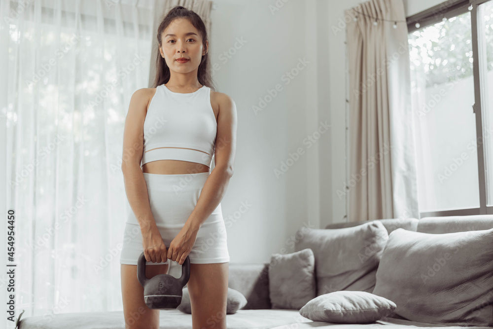Young woman exercising at home. Asian healthy woman in sportwear standing for workout at home. Home exercise.