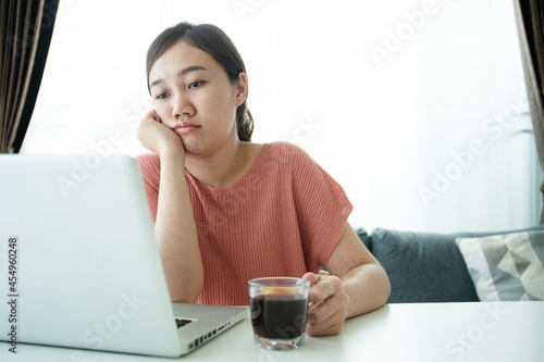 Young Asian woman bored in online meeting and work from home, woman tired in her work and online meeting.