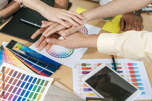group of colleagues young business hand join together for successful business meeting with color sample chart on desk in meeting room at office, interior design, architect, graphic designer concept