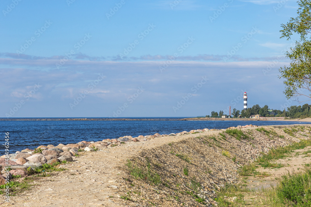 sandy road along the sea and in the distance a lighthouse sandy road along the sea and in the distance a lighthouse
