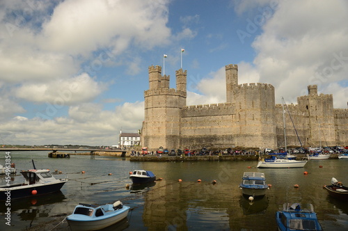 a large welsh castle in front of a harbour full of boats