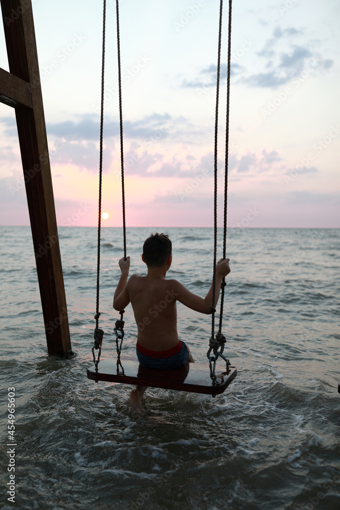 Kid sitting on swing in Sea of Azov
