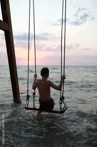 Kid sitting on swing in Sea of Azov