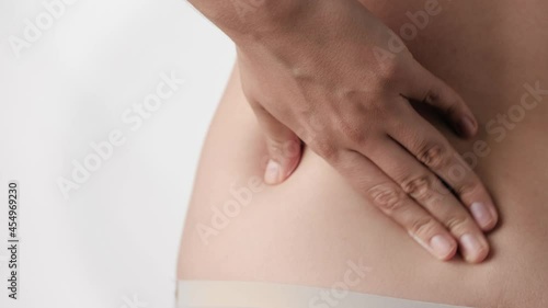 Wallpaper Mural Backache. Female hand makes circular movements along lower back, hands rub cream into skin. Close-up and slow motion Torontodigital.ca