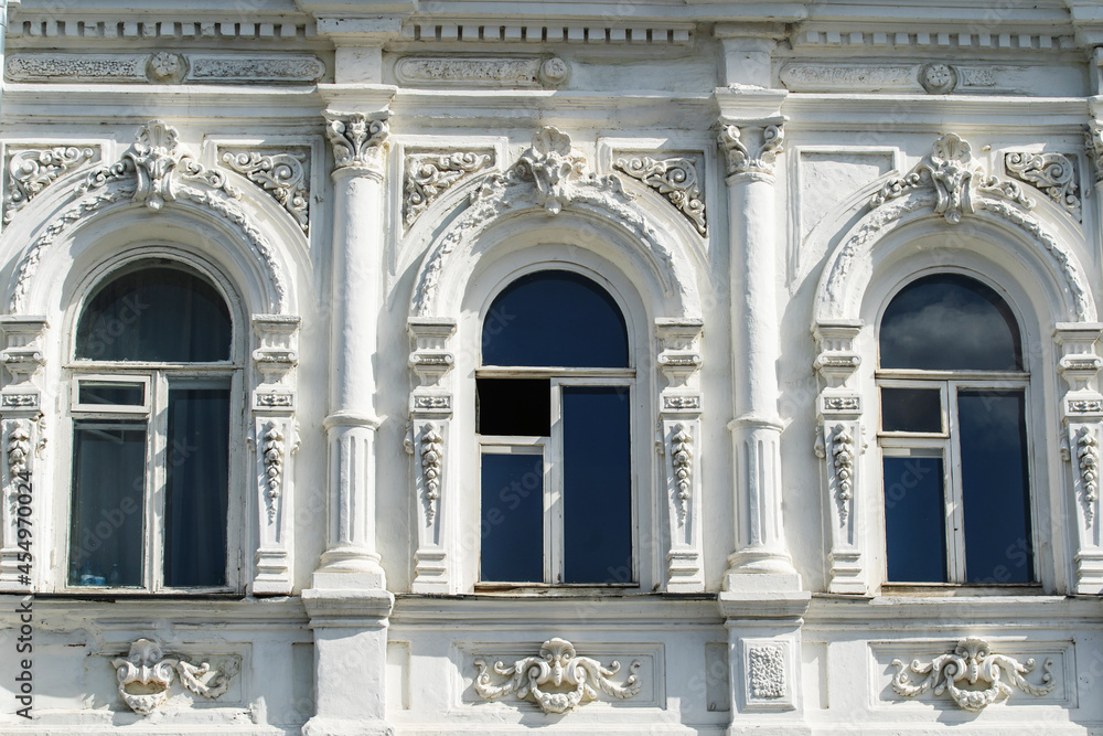 Fototapeta premium The facade of an old building with plaster ornaments and arched windows. Flat lay of the frame. Close-up