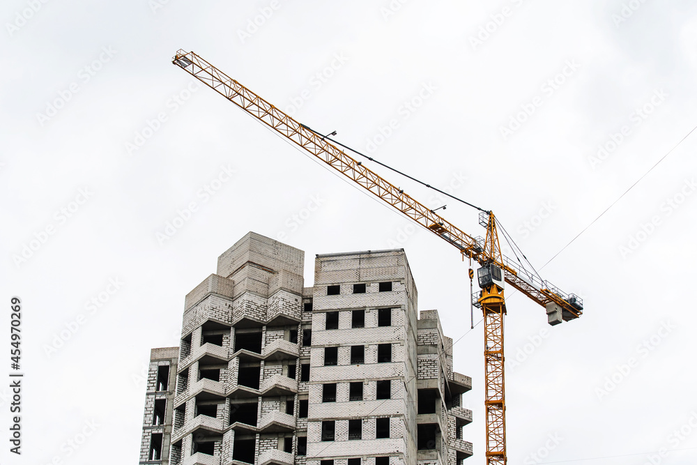 A fragment of a white brick apartment building under construction against the background of a tower crane. Close-up A fragment of a white brick apartment building under construction against the background of a tower crane. Close-up