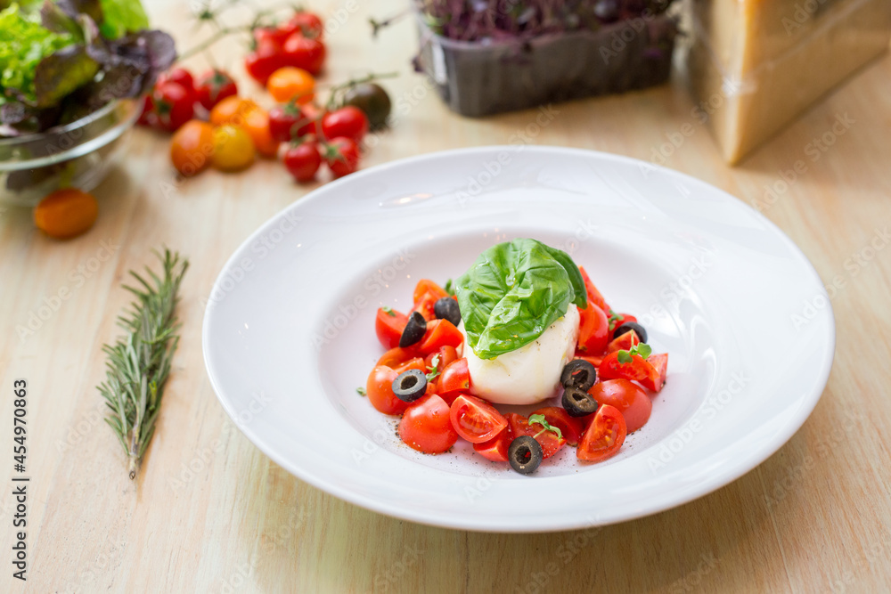 Plate with fresh salad with tomatoes, basil leaves and mozzarella Plate with fresh salad with tomatoes, basil leaves and mozzarella