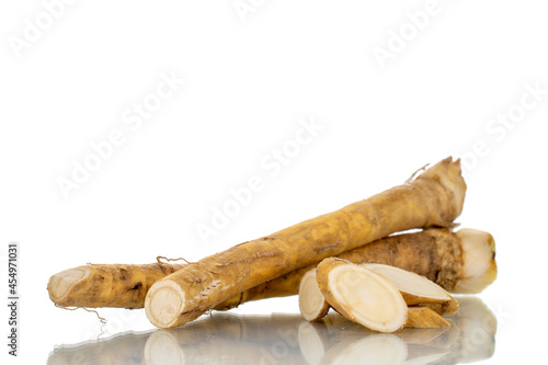 Two whole spicy horseradish roots and slices, close-up, isolated on white.