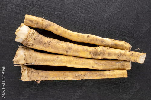 Several ripe horseradish roots on a slate stone, close-up, top view.