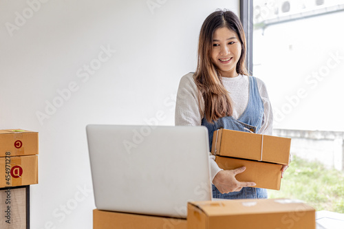 The owner of the online store holds two parcel boxes, she is checking the order balance and preparing for delivery, a parcel for packing the goods. Online selling and online shopping concepts.