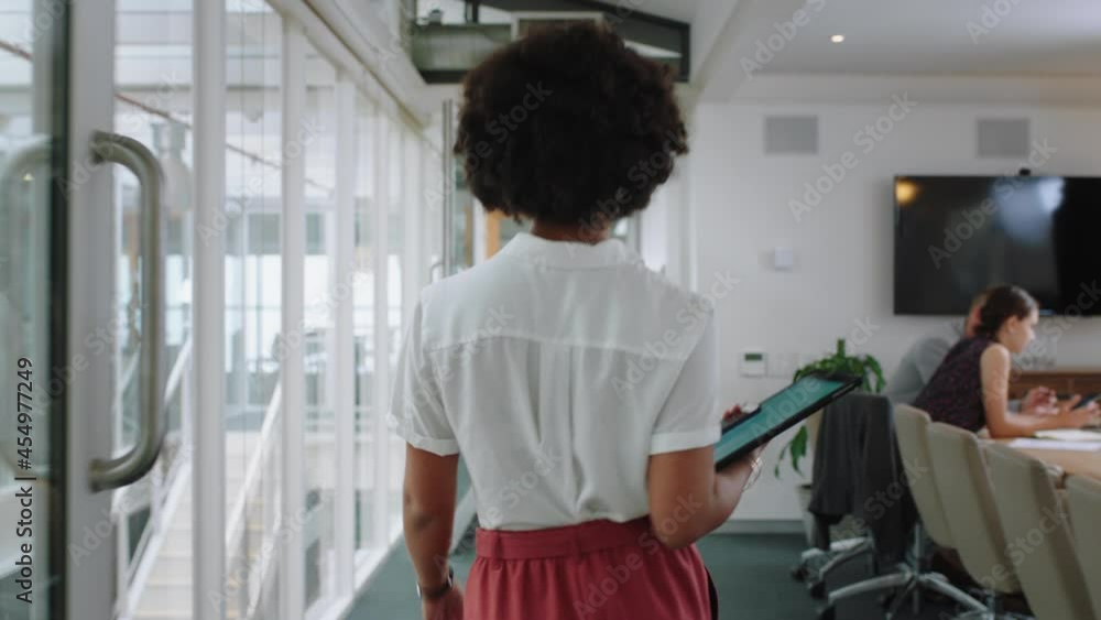 rear view mixed race business woman walking through office holding tablet computer successful career in corporate workplace 4k rear view mixed race business woman walking through office holding tablet computer successful career in corporate workplace 4k