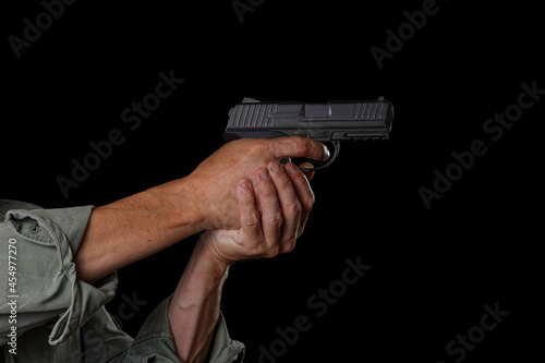 Male hands hold a handgun and aiming its to target. Isolated on black.