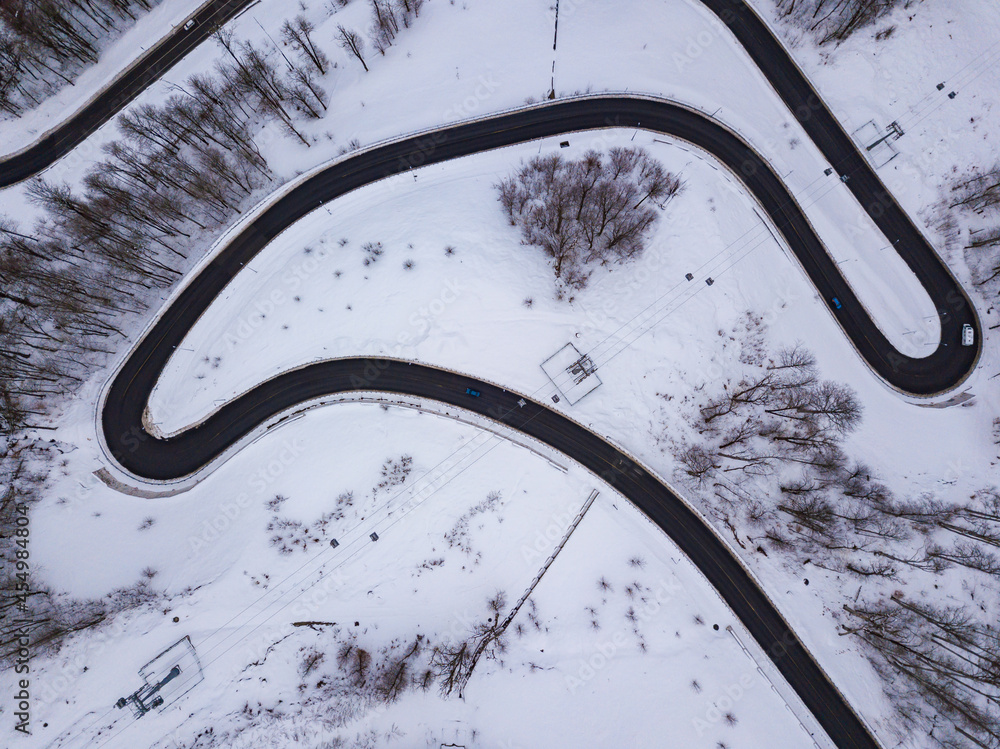 Winter aerial top view of the road to Olympic mountain village Roza Plato. Beautiful winter landscape from drone.