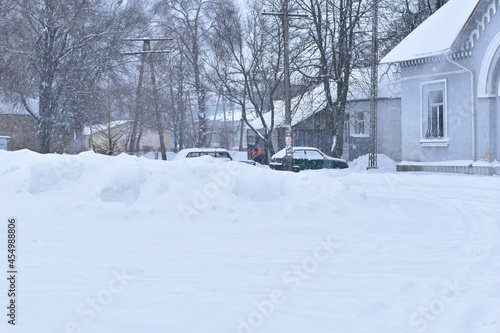 Winter. Snowing. Snowdrifts lie on a rural street, cars are parked in the parking lot. © Михаил Жигалин