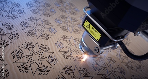 Laser cutter close up, cutting geometric patterns on a wooden board.  photo