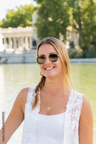 Portrait of a young blonde white girl dressed in a white tank top and sunglasses