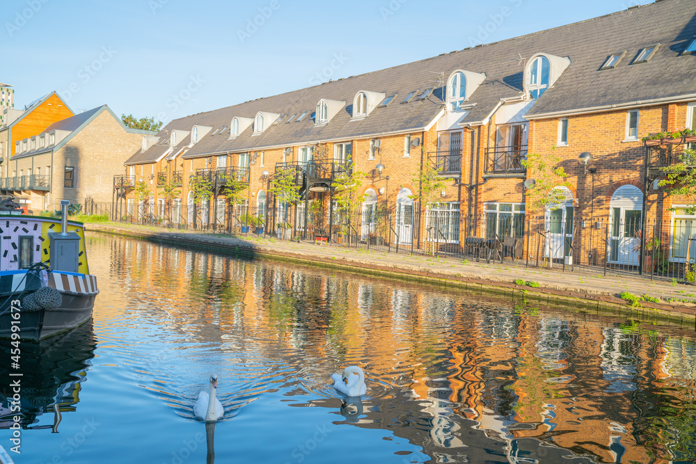 Obraz premium Canal-side apartments reflected in calm water in morning light in Bow Wharf area Hertford Union Canal of London