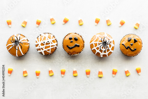 Top down view of a row of Halloween decorated cupcakes with lines of candy corn.