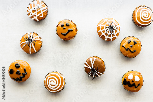 Many Halloween decorated cupcakes scattered about against a light background.