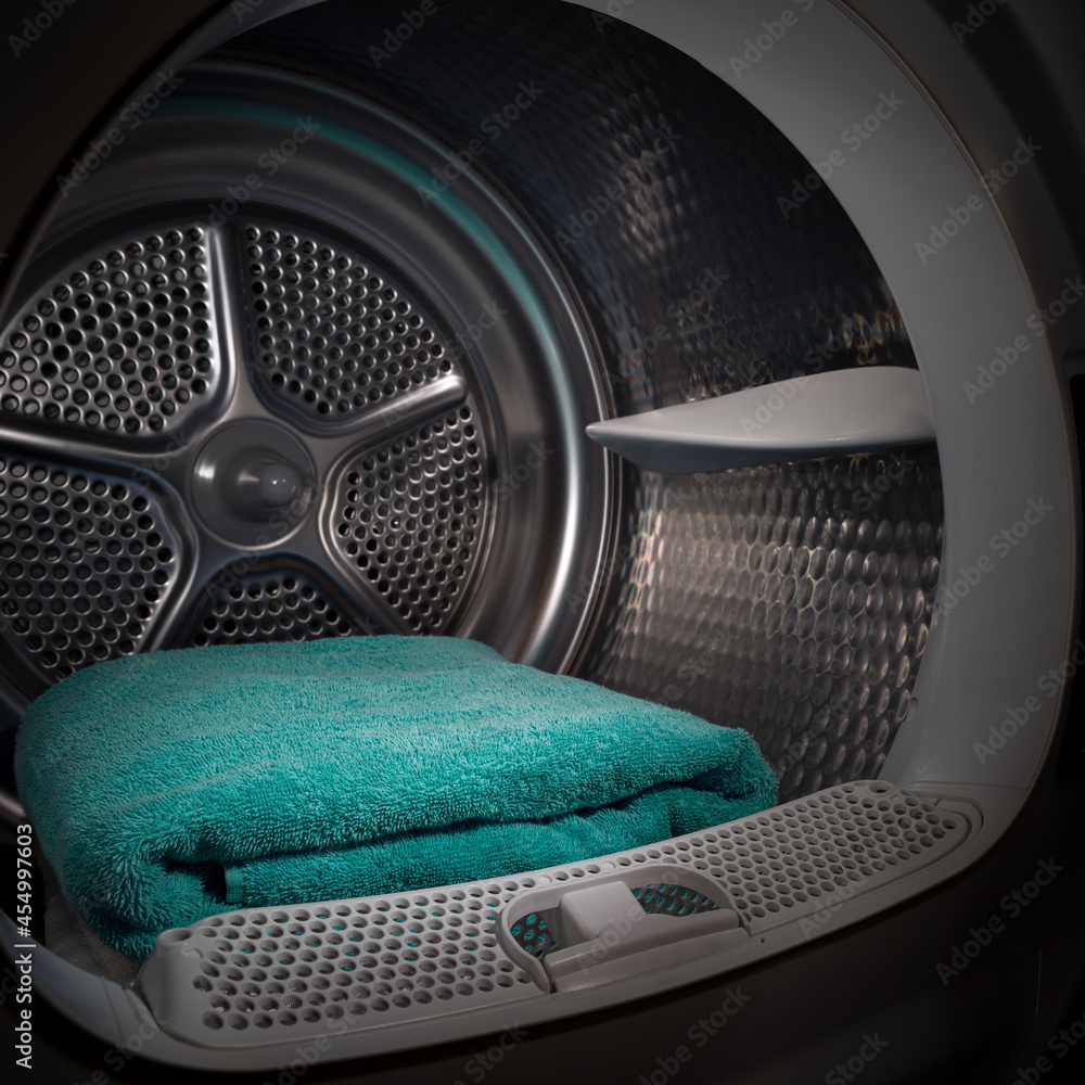 Turquoise towels are stacked in the tumble dryer. Laundry. Clean concept. Washing machine with open door Turquoise towels are stacked in the tumble dryer. Laundry. Clean concept. Washing machine with open door