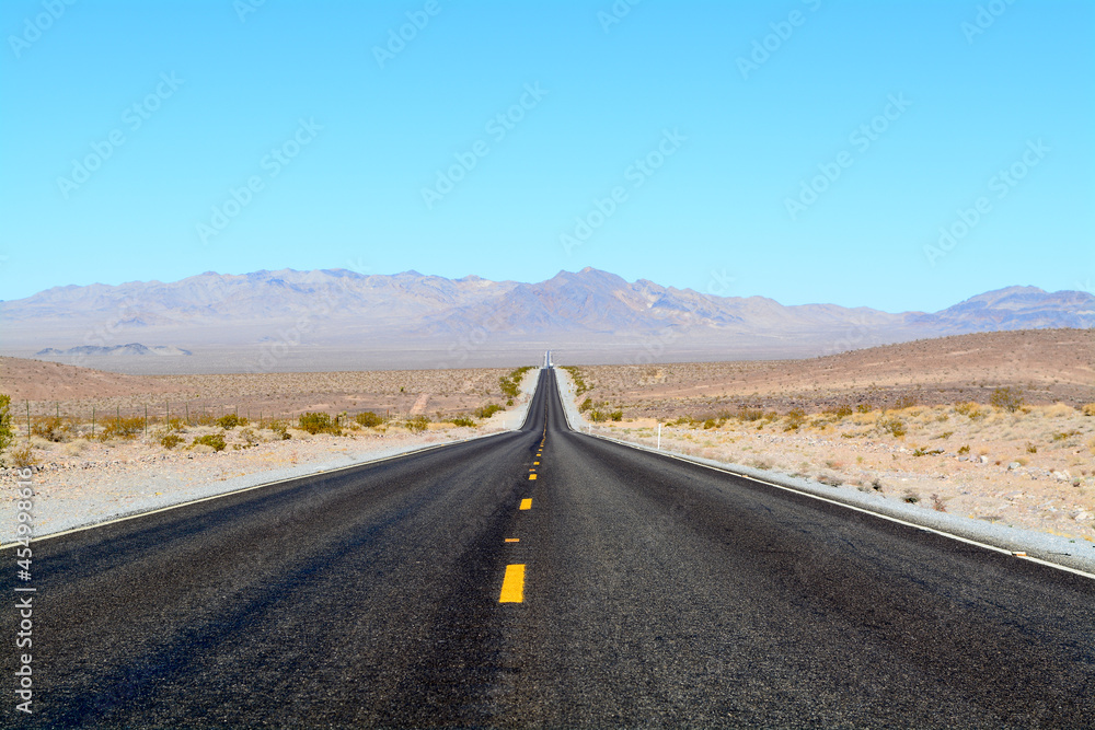 Long Road in Desert - Two-Lane Highway With Blue Sky and Hills in Background