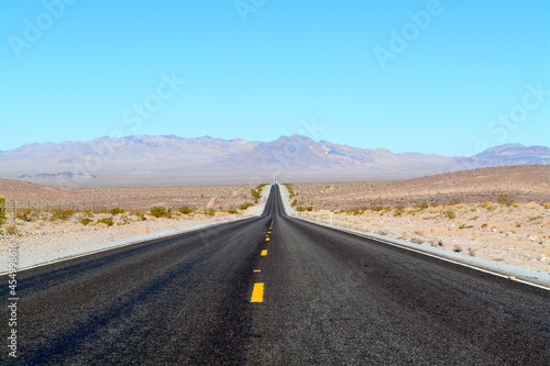 Long Road in Desert - Two-Lane Highway With Blue Sky and Hills in Background © Donald Rock