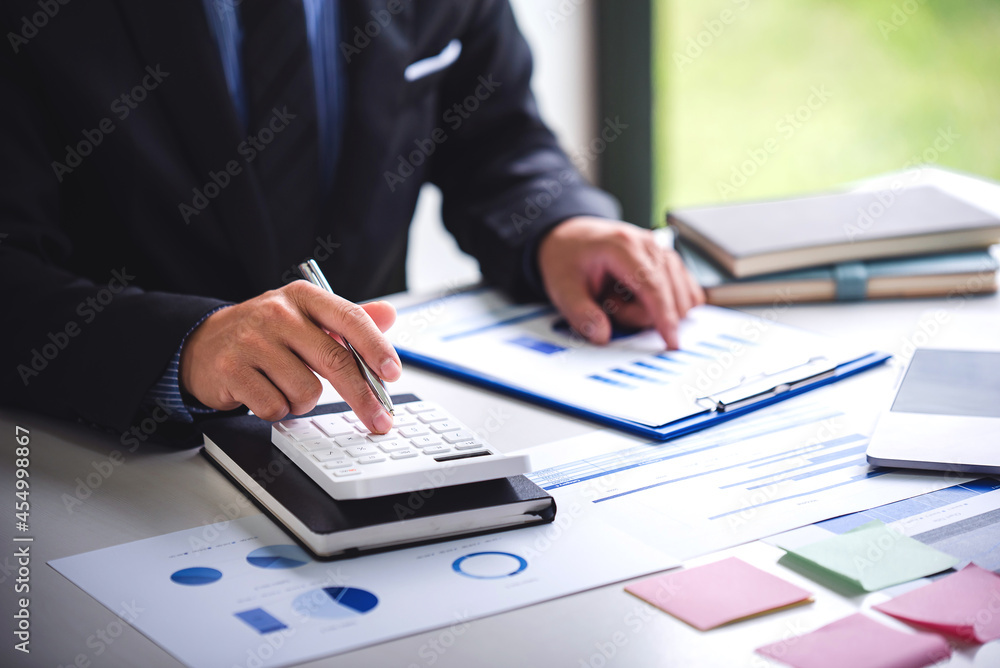 Businessman calculating on charts and graphs showing successful performance business idea Businessman calculating on charts and graphs showing successful performance business idea