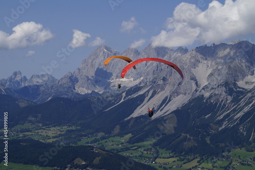 two friends paragliding in the Alps of the Schladming-Dachstein region in Austria 