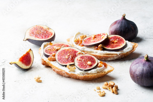 Bruschettas with cheese, raw figs and jam, walnut on table. Fresh bread. Flat lay