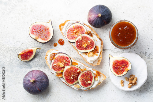 Bruschettas with cheese, raw figs and jam, walnut on table. Fresh bread. Flat lay. Top view
