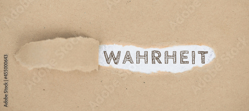 The words the truth standing on a ripped up paper,german language, Wahrheit